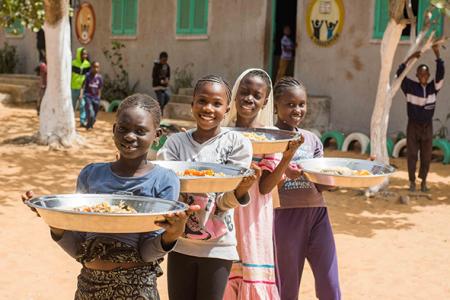 Enfants portant des plats devant une école, Dakar © grdr