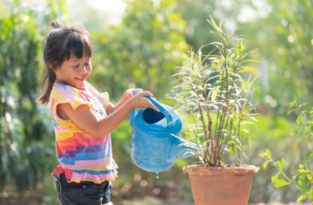 Photo d'une petite fille arrosant une plante